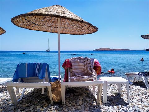 Palamutbükü sahilinde şemsiyeler ve açıkta Palamut Adası
